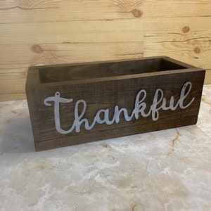 May include: A wooden box with a dark brown stain and the word "Thankful" in silver metal letters.