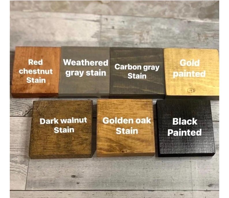 K&ouml;nnte beinhalten: Sieben quadratische Holzbl&ouml;cke in zwei Reihen, jeder mit einem eigenen Finish und wei&szlig;en Textbeschriftungen: Red chestnut Stain, Weathered gray stain, Carbon gray Stain, Gold painted, Dark walnut Stain, Golden oak Stain und Black Painted.