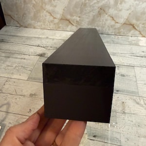 K&ouml;nnte beinhalten: Ein langer, rechteckiger Block mit einer glatten, mattschwarzen Oberfl&auml;che. Das Objekt hat scharfe, definierte Kanten und ein solides, einheitliches Erscheinungsbild, das sich horizontal in einer einfachen, geometrischen und l&auml;nglichen Prismenform erstreckt.