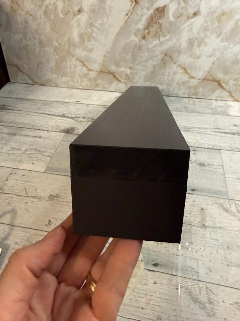 K&ouml;nnte beinhalten: Ein langer, rechteckiger Block mit einer glatten, mattschwarzen Oberfl&auml;che. Das Objekt hat scharfe, definierte Kanten und ein solides, einheitliches Erscheinungsbild, das sich horizontal in einer einfachen, geometrischen und l&auml;nglichen Prismenform erstreckt.