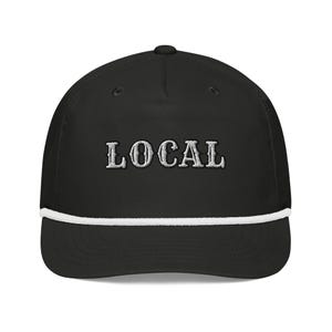 Pode incluir: Boné de beisebol preto com a palavra "LOCAL" bordada em branco. O boné tem um detalhe de corda branca ao longo da aba.