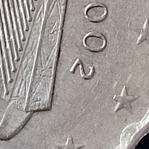 Könnte beinhalten: Nahaufnahme einer Silbermünze mit der Jahreszahl 2002. Die Münze zeigt ein Harfendesign und zwölf Sterne am Rand.
