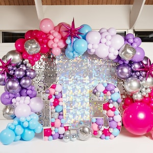 May include: A balloon arch made of pink, purple, silver, and blue balloons with disco ball balloons and star-shaped balloons. The arch is in front of a silver sequin backdrop with two large numbers, 13, made of balloons.