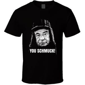 May include: Black t-shirt with a white image of a man wearing a hat and the text "You Schmuck!"