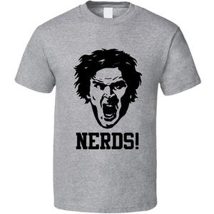 May include: A heather gray t-shirt featuring a black graphic of a person's face with an open mouth and the word "NERDS!" in bold, black letters. The shirt is a classic crew neck style.