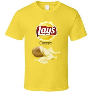 May include: A bright yellow short-sleeve t-shirt featuring the Lay's logo in red and yellow with the text Classic below it. Below the text is a graphic of a whole brown potato next to several thin, light-colored potato chips on the chest area.