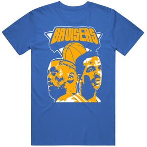 May include: A royal blue short-sleeve t-shirt featuring a graphic print in yellow and white. The design displays the text BRUISERS above a basketball and two stylized portraits of basketball players facing in opposite directions.