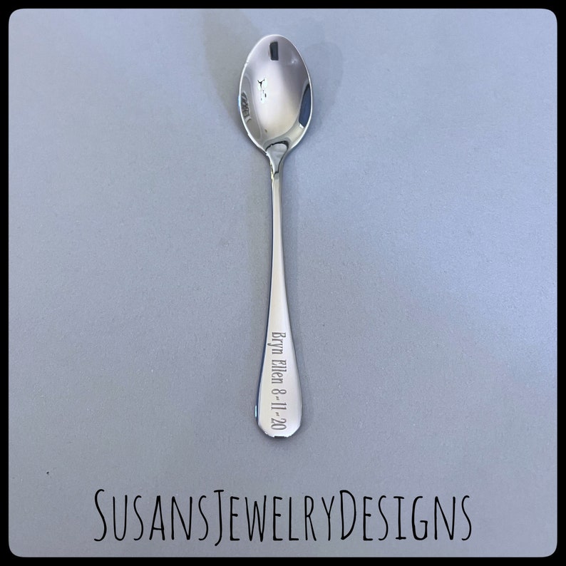 Puede incluir: Una cuchara plateada pulida con un cuenco redondeado y un mango delgado. El mango est&aacute; grabado con el nombre "Bryn Ellen 8-11-20". La cuchara est&aacute; centrada sobre un fondo gris. El texto "SUSANSJEWELRYDESIGNS" est&aacute; en la parte inferior.