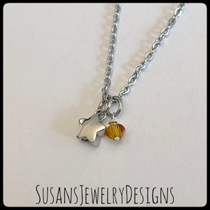 May include: A silver chain necklace with a silver star charm and a small amber-colored crystal bead.