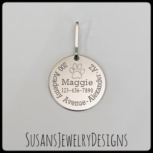 May include: Silver round dog tag with engraved text: "200 Academy Ave - Alexander, NY" and "Maggie 123-456-7890". A paw print is above the name.