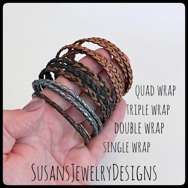 May include: A hand holding a stack of braided leather bracelets in various colors and widths, including brown, black, and silver. The bracelets are labeled "Quad Wrap", "Triple Wrap", "Double Wrap", and "Single Wrap".