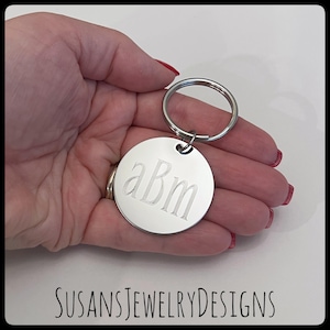May include: Silver keychain with a round tag engraved with the monogram "aBm".