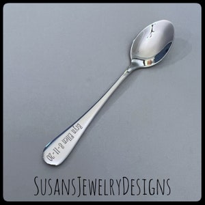 Puede incluir: Una cuchara plateada brillante con un mango largo. La cuchara tiene el texto grabado "Bryn Ellen 8-11-20" en el mango. El texto "SUSANSJEWELRYDESIGNS" est&aacute; en la parte inferior de la imagen.