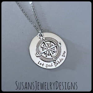 May include: Silver necklace with a compass charm and the words "let god guide you" engraved on the pendant.