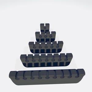 May include: Five black plastic cable organizers of varying sizes, stacked in a pyramid shape. The organizers have multiple slots for holding cables and wires.