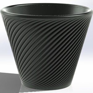 Könnte beinhalten: Eine schwarze Tasse mit einem strukturierten Spiralmuster. Die Tasse hat eine breite Öffnung und verjüngt sich zur Basis hin. Die Tasse besteht aus einem dunklen Material und steht vor einem weißen Hintergrund.