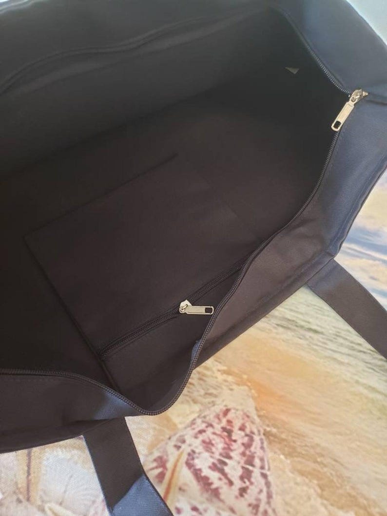 May include: Black canvas tote bag with a zippered pocket and a zipper closure. The bag has two handles.