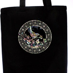 May include: Black tote bag with a circular design featuring a bird perched on a branch with flowers. The design is made of iridescent mother-of-pearl inlay.