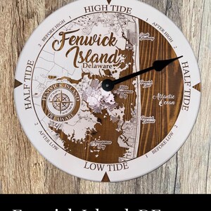 May include: A white and brown wooden clock with a map of Fenwick Island, Delaware. The clock face has the words "High Tide", "Low Tide", "Half Tide", and "Before High" and "After High". The clock hands are black.