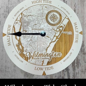 May include: A white and brown wooden tide clock with a map of Wilmington, North Carolina. The clock face has the words "High Tide", "Low Tide", "Half Tide", and "Wilmington, North Carolina".