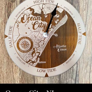 May include: A wooden clock with a map of Ocean City, New Jersey. The clock face is white with brown markings and the words "High Tide", "Low Tide", "Half Tide", "After High", "After Low", "Before High", and "Before Low". The clock hands are black and the clock is set to 12:00. The clock is surrounded by a brown wooden frame.