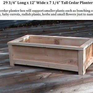Op de afbeelding: Een cederhouten plantenbak, 75 cm lang, 30 cm breed en 18,5 cm hoog, gemaakt van natuurlijk hout. De plantenbak staat op een houten oppervlak.