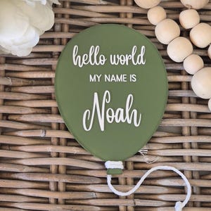 May include: A green balloon with the text "hello world my name is Noah" in white lettering. The balloon is tied with a white string.