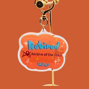 May include: A gold-colored earring display stand with a heart-shaped top. The earring features a cloud-shaped charm with the word "Retired" in blue, and the text "Archive of Our Own User". The charm is orange with white accents.