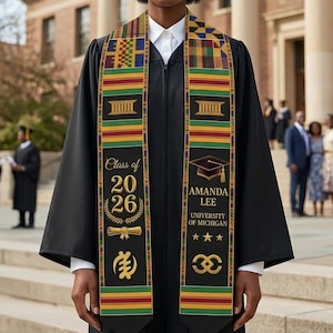 May include: A person wearing a black graduation gown and a colorful sash. The sash has the text "Class of 2026" and "Amanda Lee, University of Michigan." The background shows a university building and other graduates.