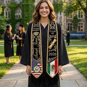 Può includere: Una laureata sorridente indossa una toga e una stola nere. La stola nera ha finiture dorate e presenta il testo "Columbia University", "Class of 2026" e il nome "Sarah Jane". La stola mostra anche le bandiere americana e messicana.