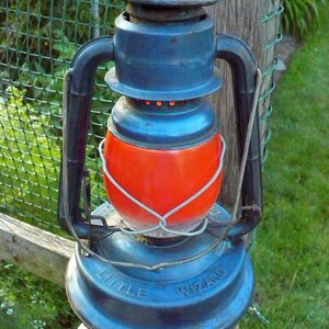 May include: A blue metal lantern with a red glass globe and the words "Little Wizard" on the base.