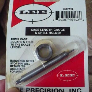 May include: A Lee Precision Case Length Gauge & Shell Holder kit. The package is white and red with the Lee logo and product information. The kit includes a gauge and shell holder. The text on the package reads "300 WIN".
