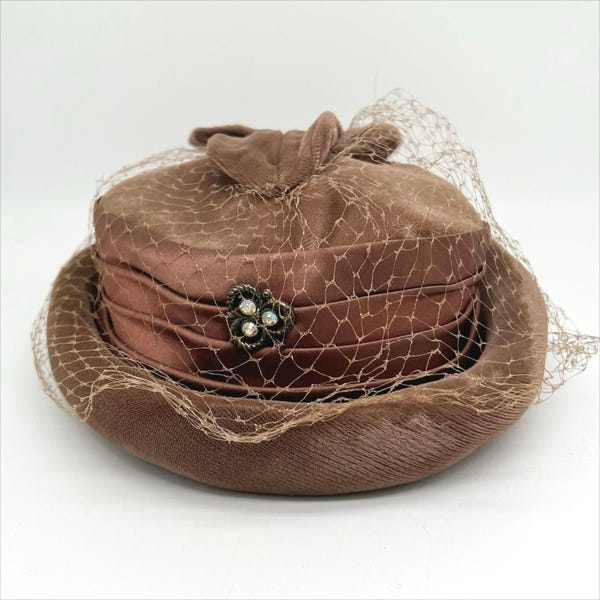 Sombrero estilo pastillero vintage de terciopelo marrón de los años 50 y 60 con malla, lazo y detalle de joyas