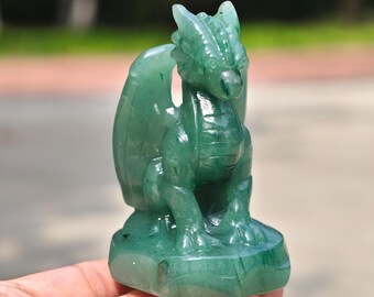 Op de afbeelding: Een gebeeldhouwd groen drakenbeeldje. De draak heeft gedetailleerde vleugels, een getextureerd lichaam en zit op een kleine basis. Het beeldje is gemaakt van een doorschijnende groene steen, met zichtbare natuurlijke patronen.