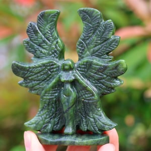 May include: Green jade stone sculpture of an angel with outstretched wings. The angel is carved in a detailed, realistic style.
