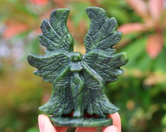 May include: Green jade stone sculpture of an angel with outstretched wings. The angel is carved in a detailed, realistic style.