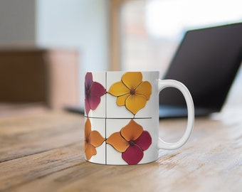 May include: White ceramic mug with a floral design. The design features four stylized flowers in shades of purple, orange, and yellow, arranged in a grid pattern. The mug has a curved handle and is set on a wooden surface.