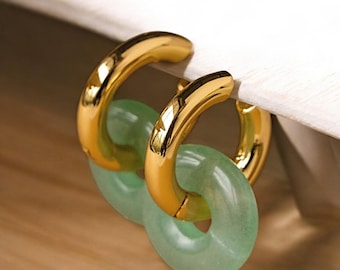 Può includere: Orecchini a cerchio dorati con un accento in pietra verde giada. Gli orecchini sono di un design semplice ed elegante.