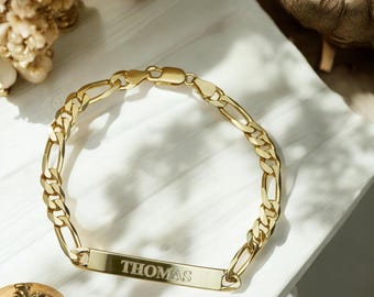 Puede incluir: Un brazalete de cadena dorada con una placa rectangular grabada con el nombre "THOMAS".
