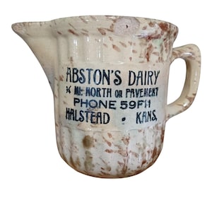 Puede incluir: Jarra de cerámica antigua con pico y asa. La jarra es de color blanco roto con motas marrones y presenta el texto "ABSTON'S DAIRY" y otros detalles en negro. Un artículo vintage.