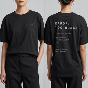 May include: Black t-shirt with the word "SYSTEM" printed on the front. The back of the shirt features the text "ERROR: TOO HUMAN" along with code snippets and the status "UNSTABLE".