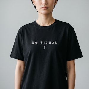 May include: Black crew neck t-shirt with the words "NO SIGNAL" printed in white, along with a small wifi symbol. The shirt is made of a soft material and has short sleeves.