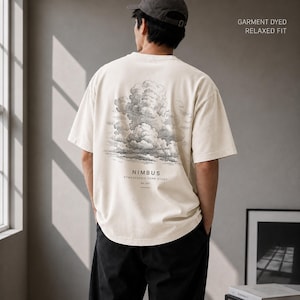 May include: An off-white short-sleeve t-shirt with a relaxed fit and garment-dyed finish. The back features a detailed grey-scale illustration of a large cloud formation with the text "NIMBUS ATMOSPHERIC FORM STUDY NO.001" printed below.