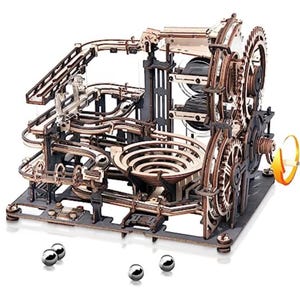 Könnte beinhalten: Ein komplexes Murmelbahn-Set aus Holz mit Rampen, Spiralen und Zahnrädern. Die Struktur besteht aus hellbraunem Holz und dunkelgrauen Akzenten. Mehrere silberne Murmeln liegen am Boden, und eine Handkurbel ist sichtbar.