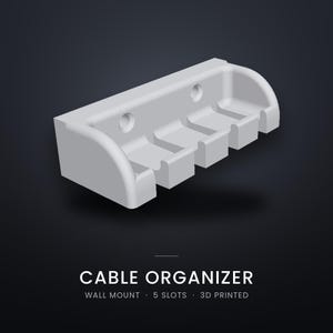 Puede incluir: Un organizador de cables de pared en color gris claro con cinco ranuras distintas para la gestión de cables. El objeto incluye dos orificios de montaje circulares en el panel posterior. El texto dice: CABLE ORGANIZER, WALL MOUNT, 5 SLOTS, 3D PRINTED.