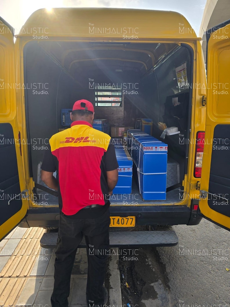 May include: A yellow DHL delivery van with its doors open, revealing packages inside. A person wearing a DHL uniform stands in front of the van. The van has a license plate with the number T4077.