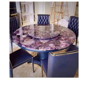 May include: A round dining table with a purple and white patterned surface, surrounded by six navy blue chairs. The table has a central rotating section and a gold trim. The chairs have a tufted back design.