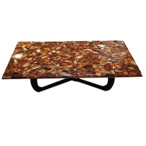 Peut inclure: Une table basse rectangulaire avec un plateau en mosaïque présentant un motif de pierres marron, beige et noires. La table a une base en métal noir incurvée. Les dimensions de la table sont d'environ 122 cm de long et 61 cm de large.