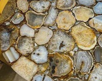 May include: A round side table featuring a tabletop composed of numerous polished, multi-colored agate slices in shades of beige, brown, gray, and white, embedded in a smooth, clear resin surface, supported by a metal frame structure.