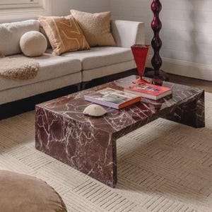 May include: A contemporary living room with a brown and white marble-effect coffee table. The table is the focal point, surrounded by a light-toned sofa, rug, and decorative elements. The room has a modern, stylish aesthetic, with a focus on texture and colour.